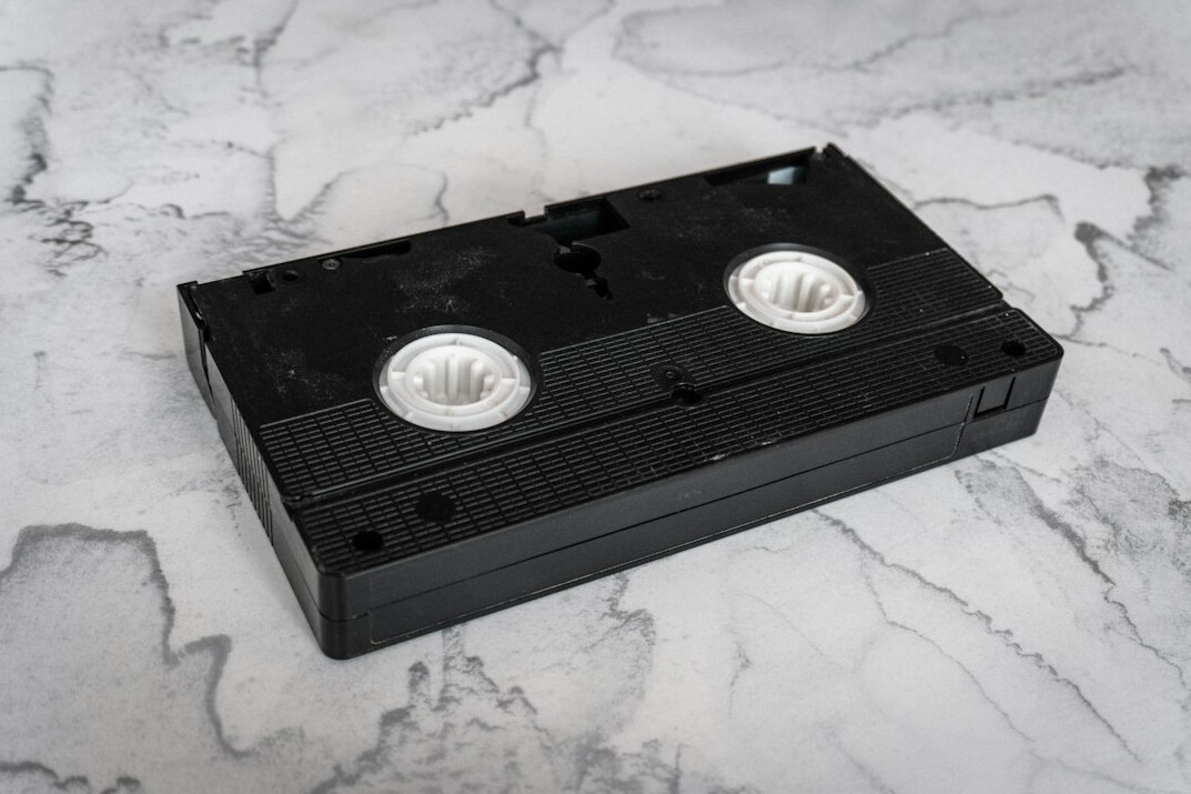 Man media historian holding an old videotape in an archive